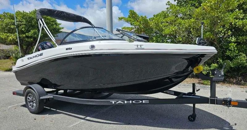 Slide: The Image of 2025 Tahoe 185 S boat on trailer, parked outdoors, surrounded by greenery. - 4