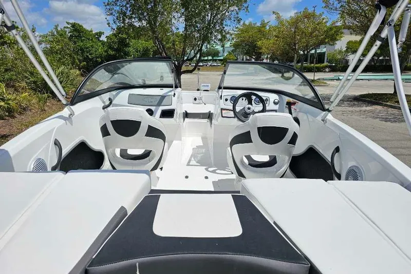 Slide: The Image of 2025 Tahoe 185 S boat interior with dual seats and dashboard, parked outdoors. - 7