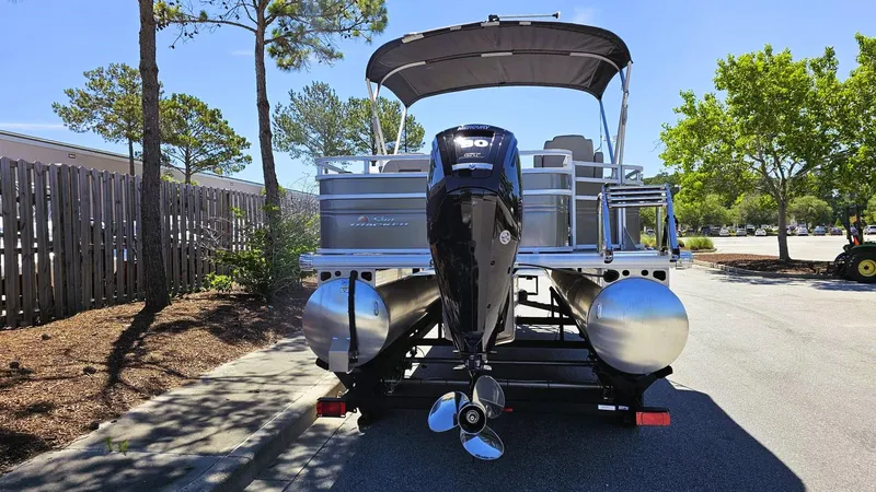 Slide: The Image of 2025 Sun Tracker Fishin' Barge 20 DLX pontoon boat with outboard motor, parked outdoors. - 3