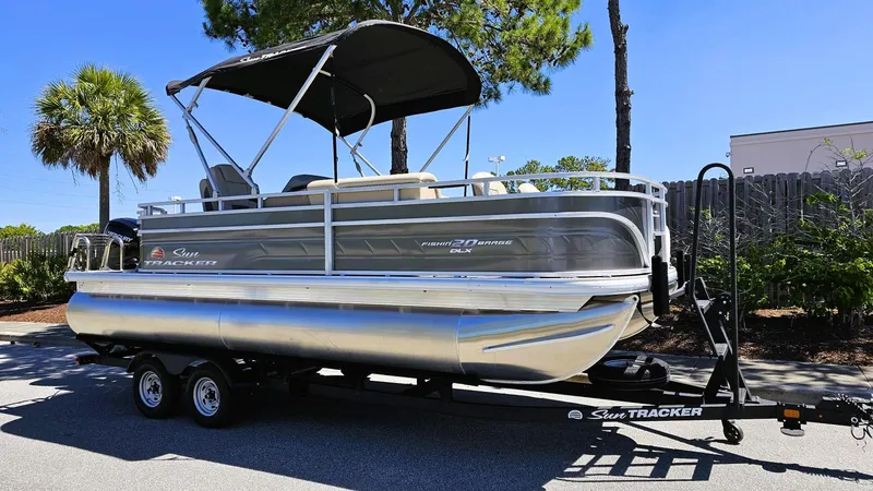 Slide: The Image of 2025 Sun Tracker Fishin' Barge 20 DLX pontoon boat on trailer, parked outdoors. - 4
