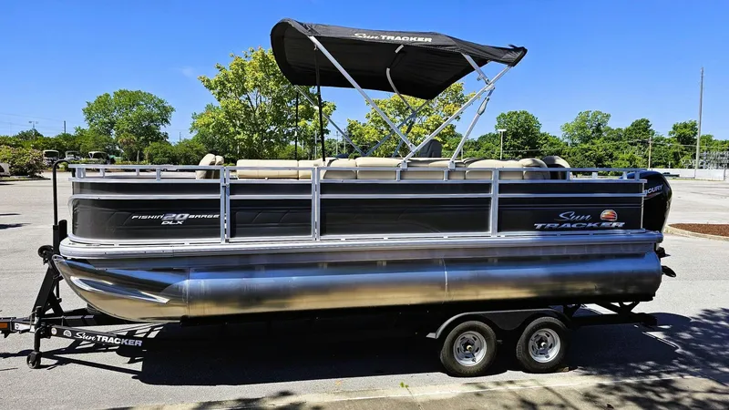 Slide: The Image of 2025 Sun Tracker Fishin' Barge 20 DLX pontoon boat on trailer, parked outdoors. - 6