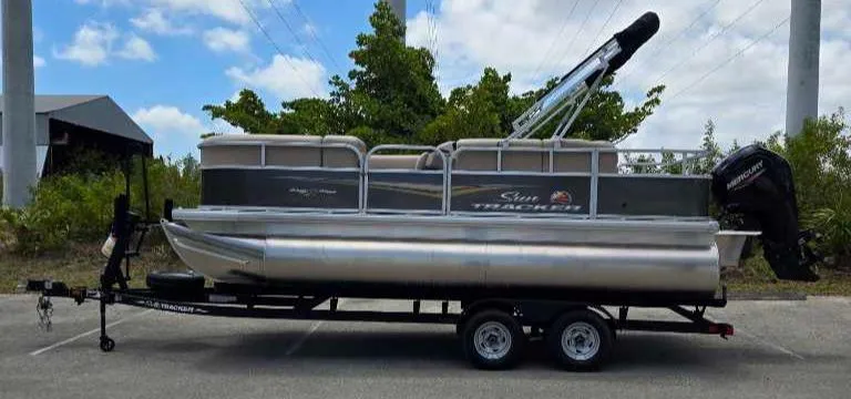Slide: The Image of 2025 Sun Tracker Party Barge 18 DLX pontoon boat on trailer, parked outdoors. - 68