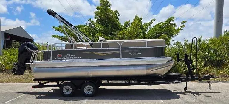 Slide: The Image of 2025 Sun Tracker Party Barge 18 DLX pontoon boat on trailer, parked outdoors. - 69