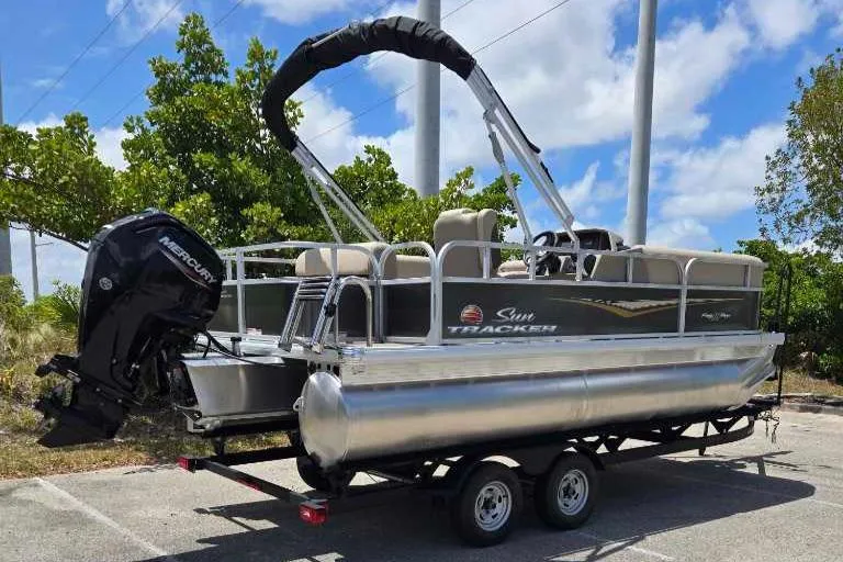 Slide: The Image of 2025 Sun Tracker Party Barge 18 DLX pontoon boat on trailer, parked outdoors. - 70