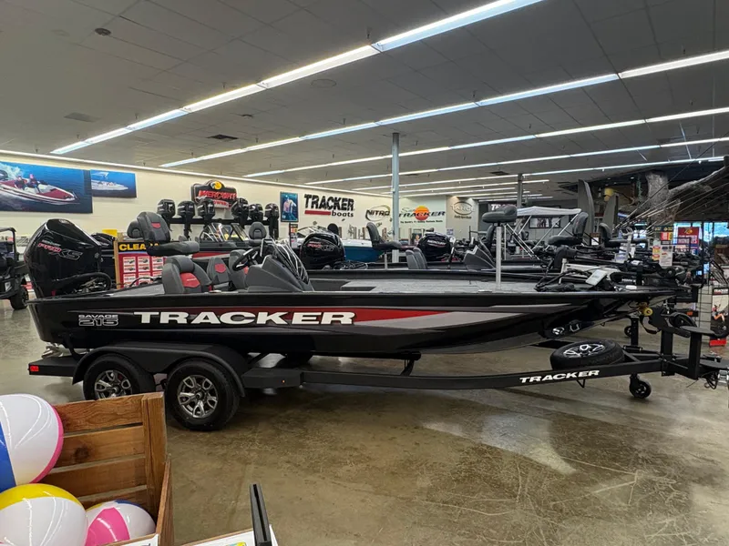 The Image of 2025 Tracker Savage 215 boat displayed in a showroom with promotional banners. - 0