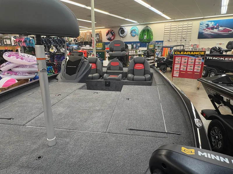 Slide: The Image of 2025 Tracker Savage 215 boat interior in showroom with seating and accessories. - 5
