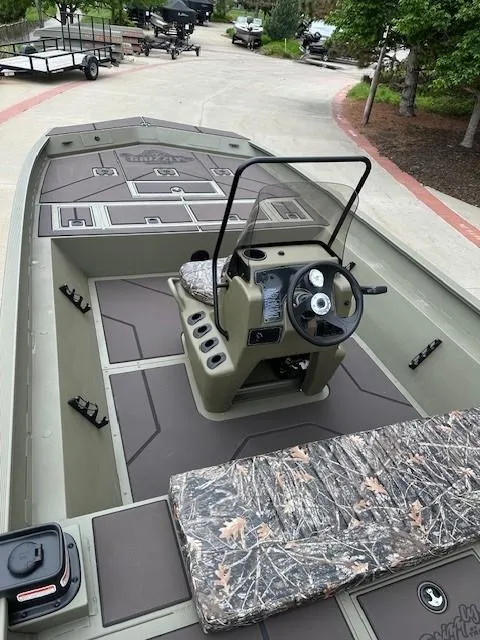 Slide: The Image of 2025 Tracker Grizzly 2072 CC boat with camo seating and steering console, parked outdoors. - 11