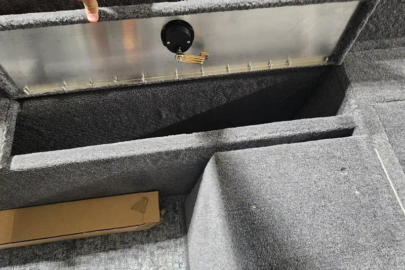 Slide: The Image of 2025 Tracker Pro Guide V-175 Combo boat storage compartment with carpeted interior and metal latch. - 12
