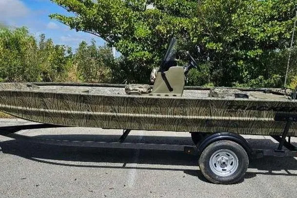 The Image of 2025 Tracker Grizzly 1860 CC boat on trailer, camo design, parked outdoors. - 0