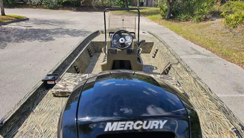 Slide: The Image of 2025 Tracker Grizzly 1860 CC boat with Mercury engine, parked outdoors. - 11