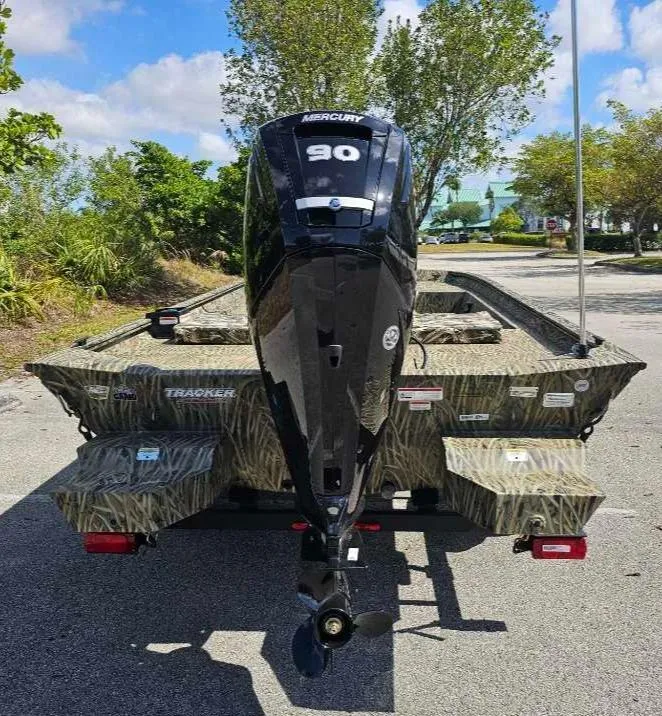 Slide: The Image of 2025 Tracker Grizzly 1860 CC boat with Mercury 90 engine, parked outdoors. - 12