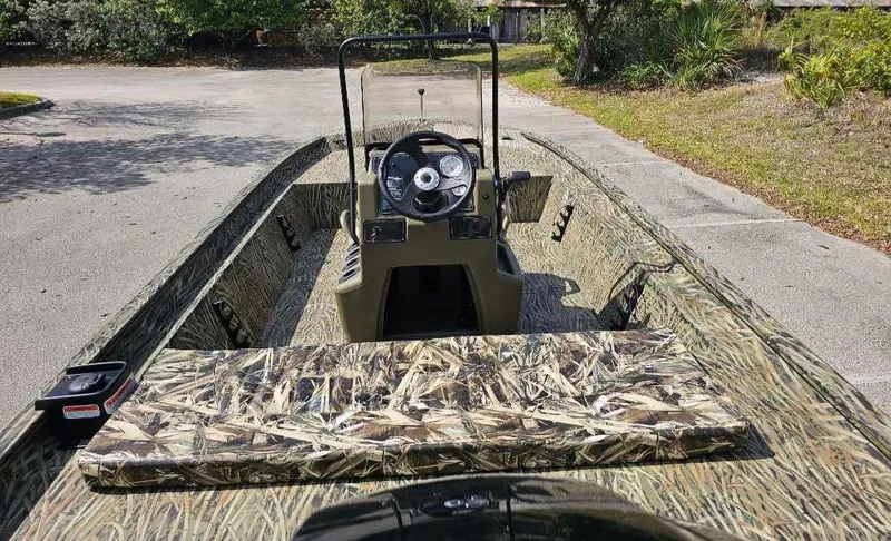 Slide: The Image of 2025 Tracker Grizzly 1860 CC boat with camouflage design, parked outdoors. - 5