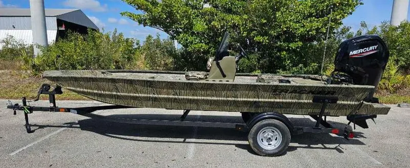 Slide: The Image of 2025 Tracker Grizzly 1860 CC boat on trailer, parked outdoors, with Mercury outboard motor. - 72