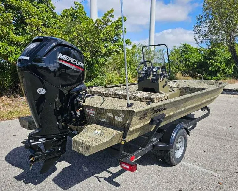 Slide: The Image of 2025 Tracker Grizzly 1860 CC boat with Mercury engine on trailer, parked outdoors. - 9