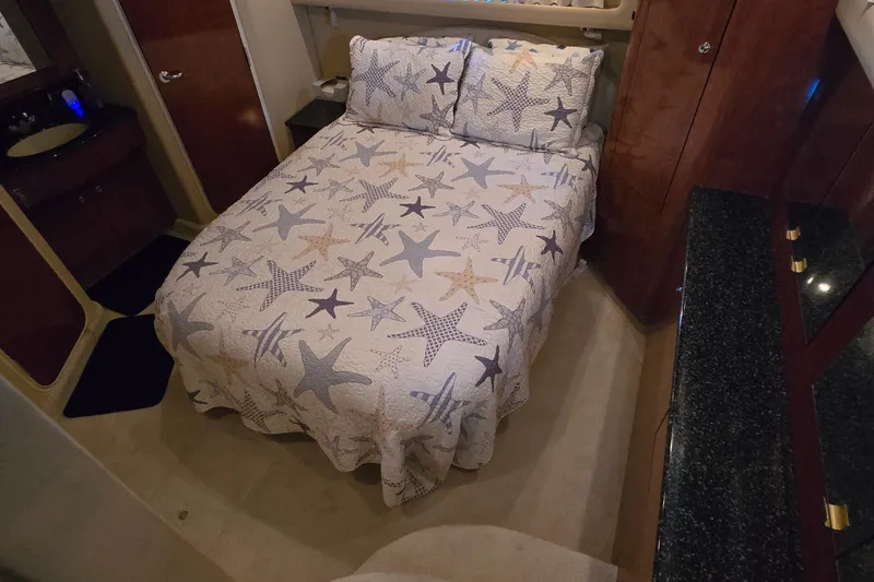 Slide: The Image of 2003 Sea Ray 390 Motor Yacht bedroom with starfish-patterned bedding and elegant wood cabinetry. - 10