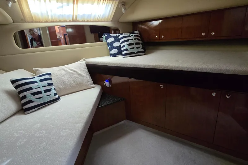 Slide: The Image of 2003 Sea Ray 390 Motor Yacht interior with cozy bedding and nautical-themed pillows. - 12