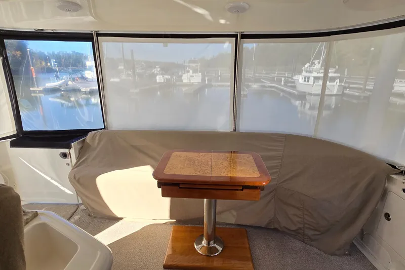 Slide: The Image of 2003 Sea Ray 390 Motor Yacht interior with covered seating and wooden table. - 24
