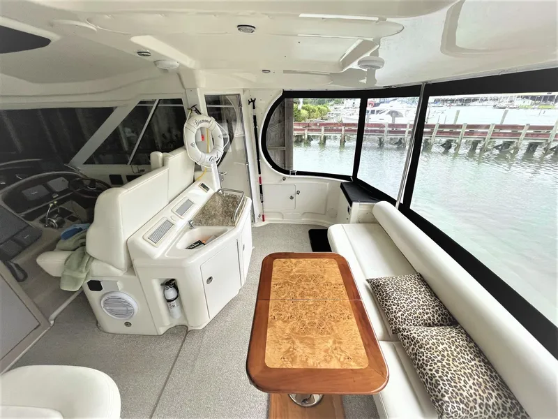 Slide: The Image of 2003 Sea Ray 390 Motor Yacht interior with helm, seating, and table overlooking water. - 25