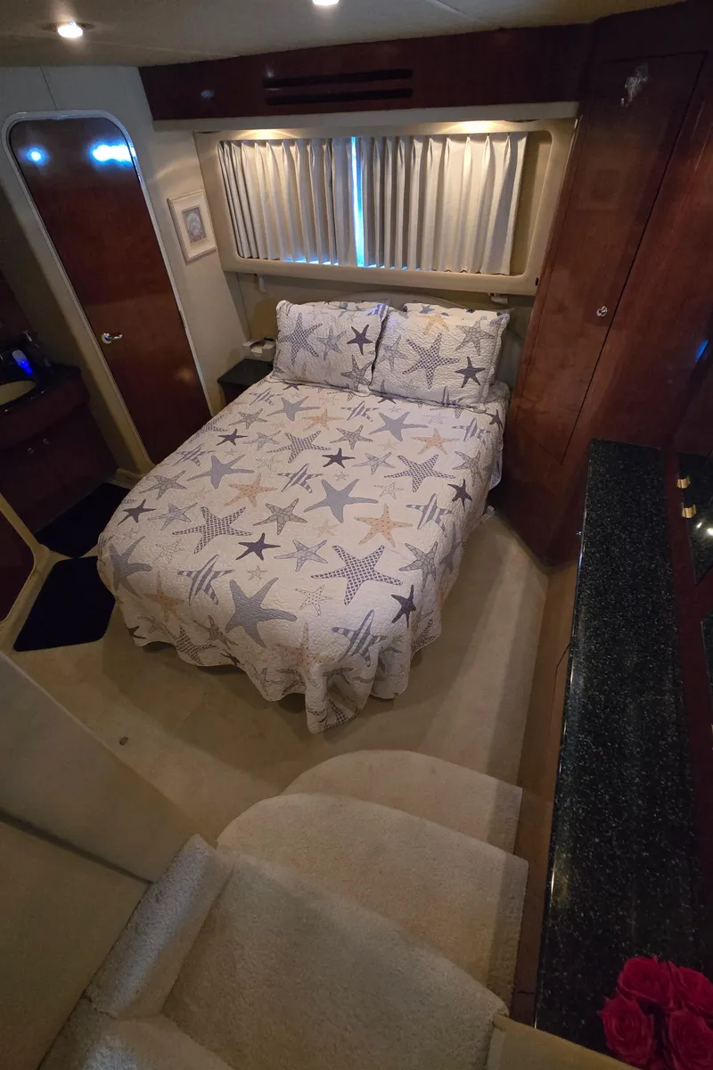 Slide: The Image of 2003 Sea Ray 390 Motor Yacht bedroom with starfish-themed bedding and elegant wood finishes. - 9