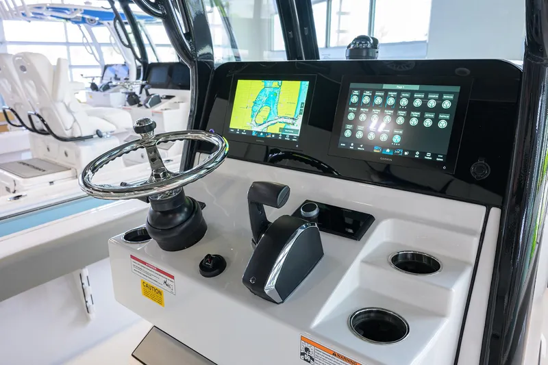 Slide: The Image of 2025 Sportsman Masters 267 Bay Boat dashboard with navigation screens and steering wheel. - 23