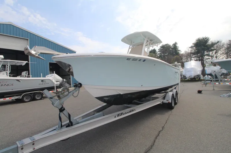 Slide: The Image of 2017 Sailfish 236 CC boat on trailer, parked outdoors near a blue building. - 4