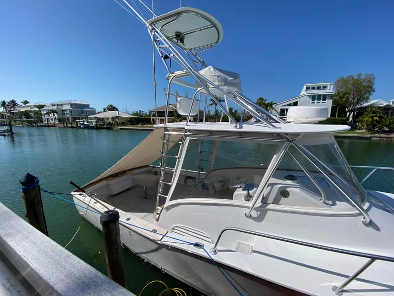 Slide: The Image of 1995 L&H 33 boat docked by waterfront homes under clear blue sky. - 2