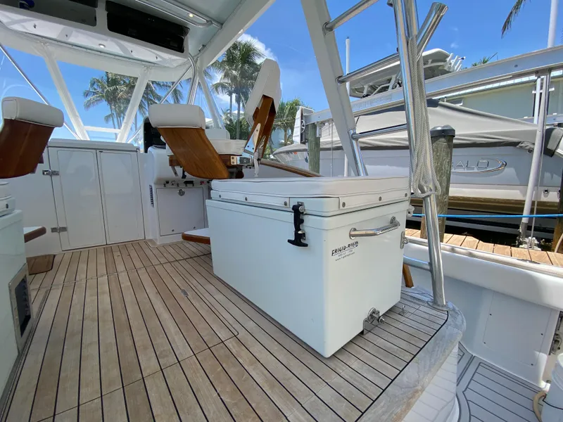 Slide: The Image of 1995 L&H 33 boat interior with wooden deck and seating, featuring a large cooler. - 22