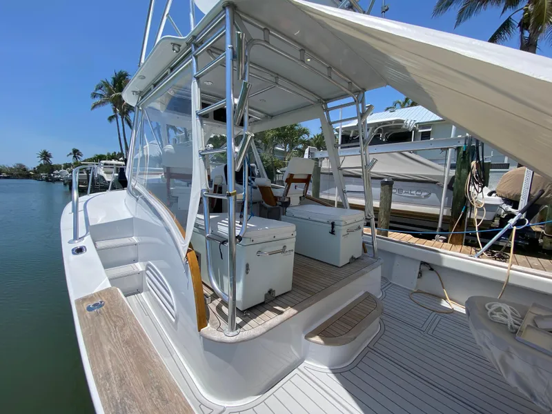 Slide: The Image of 1995 L&H 33 boat docked, featuring spacious deck and seating under clear blue sky. - 32