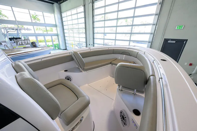 Slide: The Image of 2025 Sportsman Open 282 Center Console boat interior with cushioned seating in a showroom. - 15