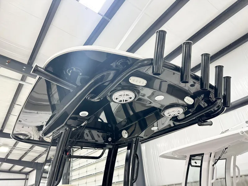 Slide: The Image of 2025 Sportsman Heritage 231 Center Console T-top with rod holders and speakers in a showroom. - 5