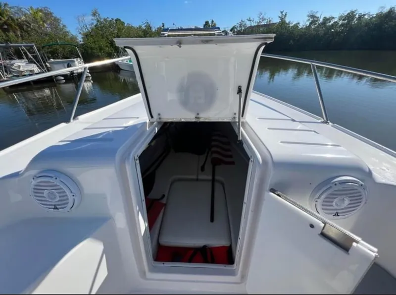 Slide: The Image of 1999 Donzi 35 ZF boat with open storage compartment, speakers, and scenic water backdrop. - 10