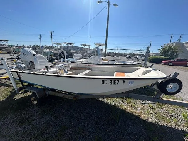 The Image of 1974 Boston Whaler 13 Sport boat on trailer, parked outdoors under clear sky. - 0