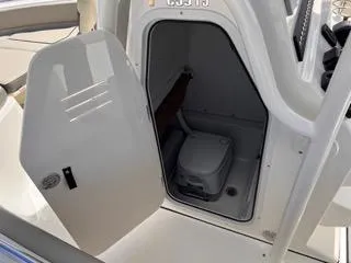 Slide: The Image of 2025 Key West 239 FS boat interior with open compartment and portable toilet. - 43