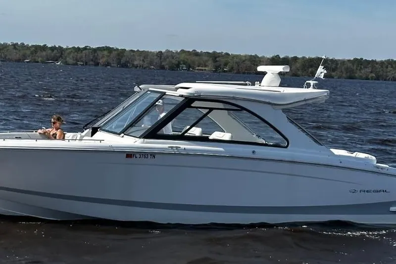 The Image of 2023 Regal LX36 boat cruising on a lake with passengers onboard. - 0