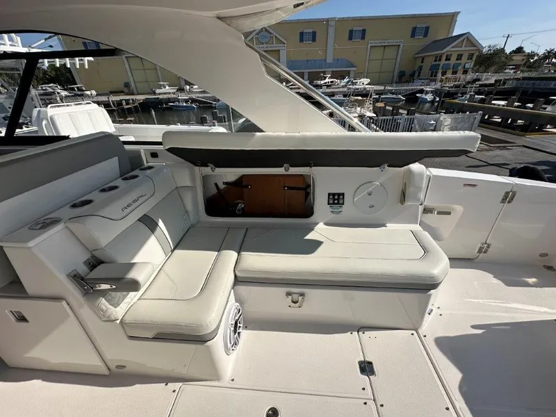 Slide: The Image of 2023 Regal LX36 boat interior with white seating and marina background. - 18