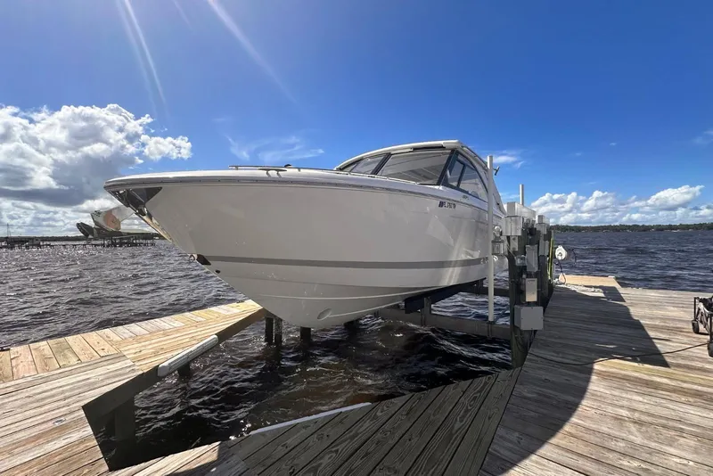 Slide: The Image of 2023 Regal LX36 boat docked on a sunny day with blue sky and clouds. - 2