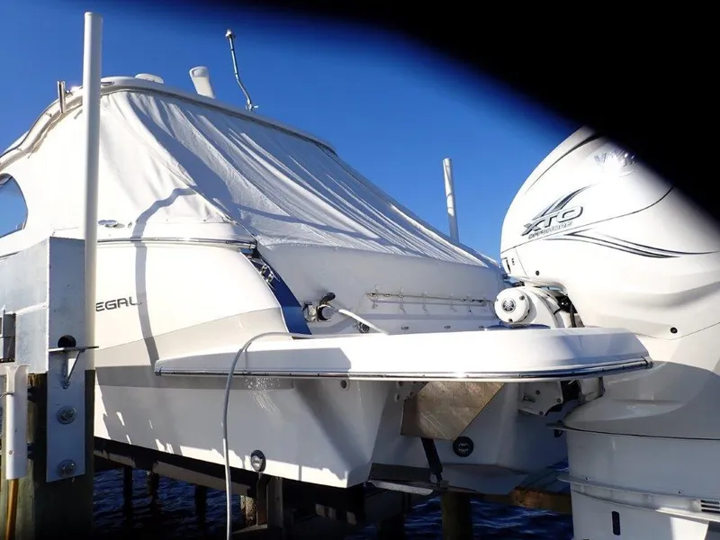 Slide: The Image of 2023 Regal LX36 boat with covered deck and outboard motor, docked on a sunny day. - 22