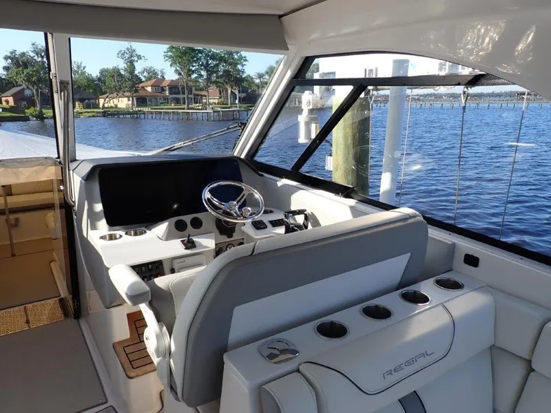 Slide: The Image of 2023 Regal LX36 boat interior with helm, steering wheel, and waterfront view. - 24