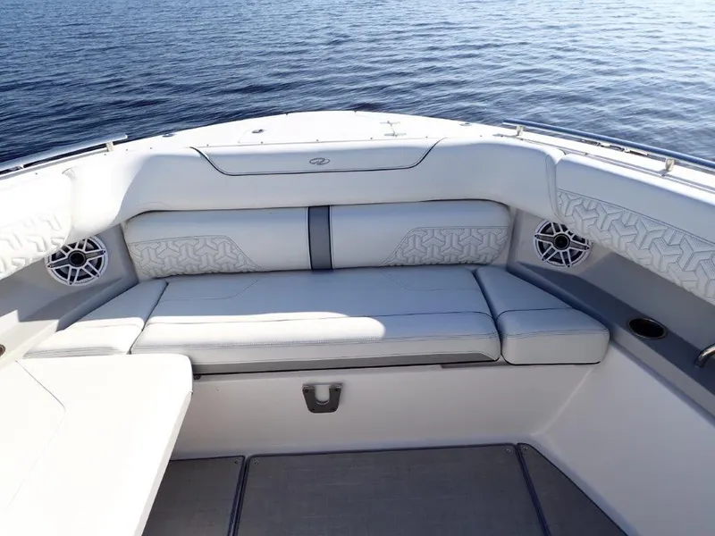Slide: The Image of 2023 Regal LX36 boat interior with cushioned seating and speakers, overlooking calm water. - 33