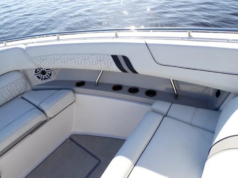 Slide: The Image of 2023 Regal LX36 boat interior with cushioned seating and cup holders on calm water. - 34
