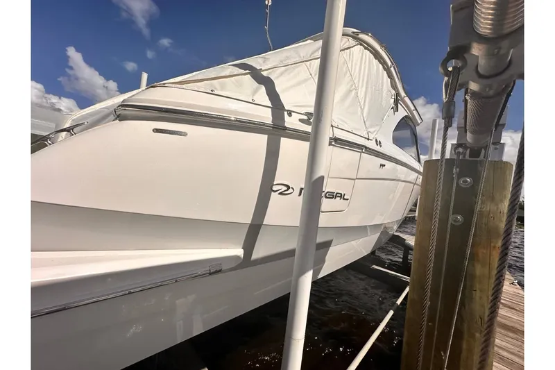 Slide: The Image of 2023 Regal LX36 boat docked, featuring sleek white design and covered canopy. - 46
