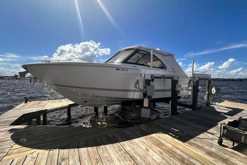 Slide: The Image of 2023 Regal LX36 boat on dock lift under sunny blue sky. - 47