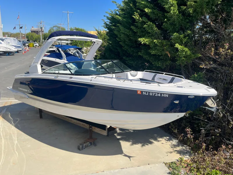 Slide: The Image of 2019 Chaparral 277 SSX boat with blue hull, docked outdoors. - 1