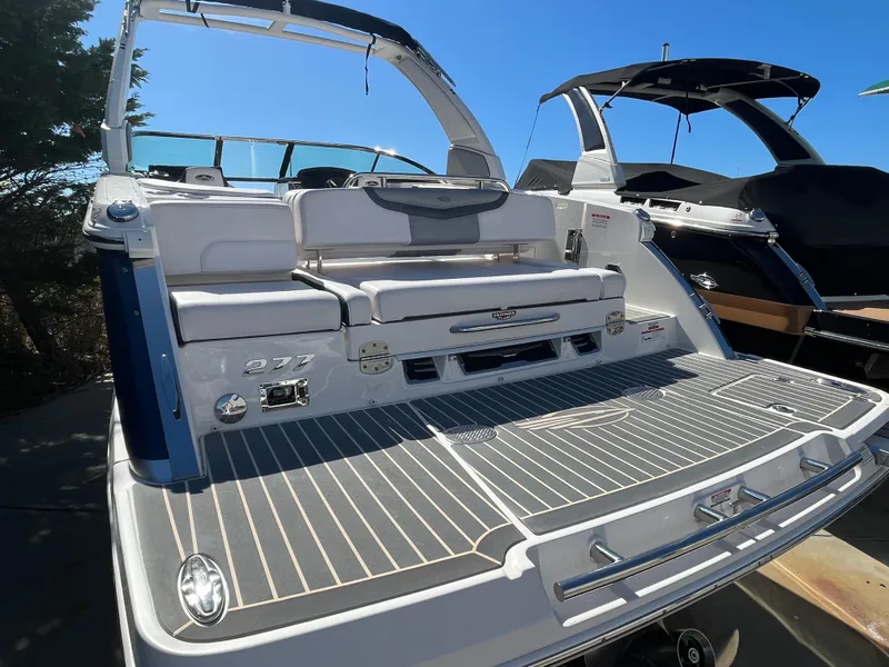 Slide: The Image of 2019 Chaparral 277 SSX boat with spacious deck and seating, docked under clear blue sky. - 10