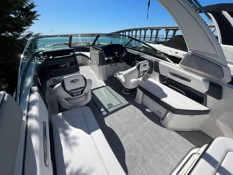 Slide: The Image of 2019 Chaparral 277 SSX boat interior with modern seating and dashboard, under clear blue sky. - 16