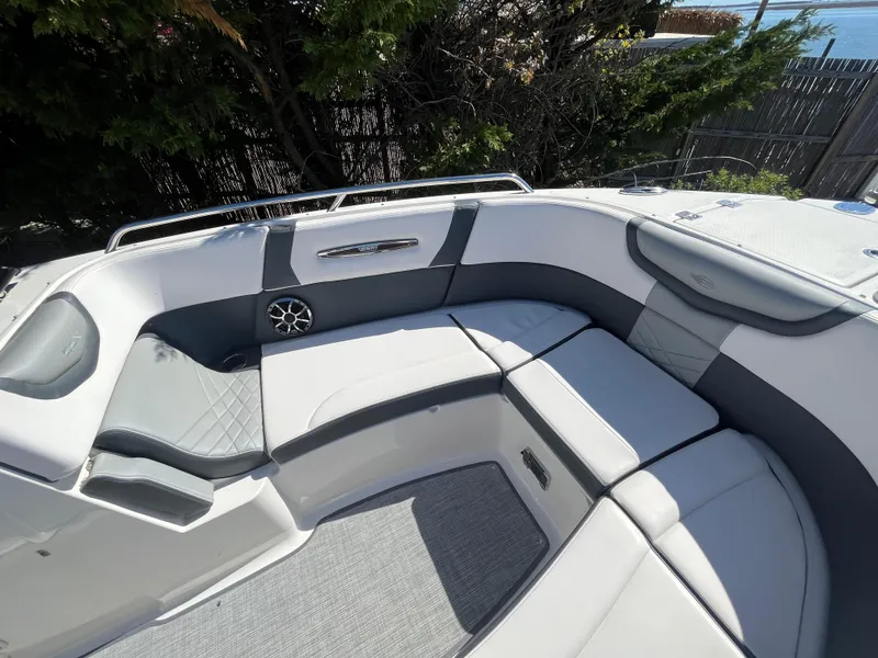 Slide: The Image of 2019 Chaparral 277 SSX boat interior with gray seating and speaker, surrounded by trees. - 37
