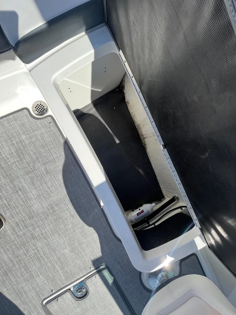 Slide: The Image of 2019 Chaparral 277 SSX boat storage compartment with gray interior and visible pump. - 42