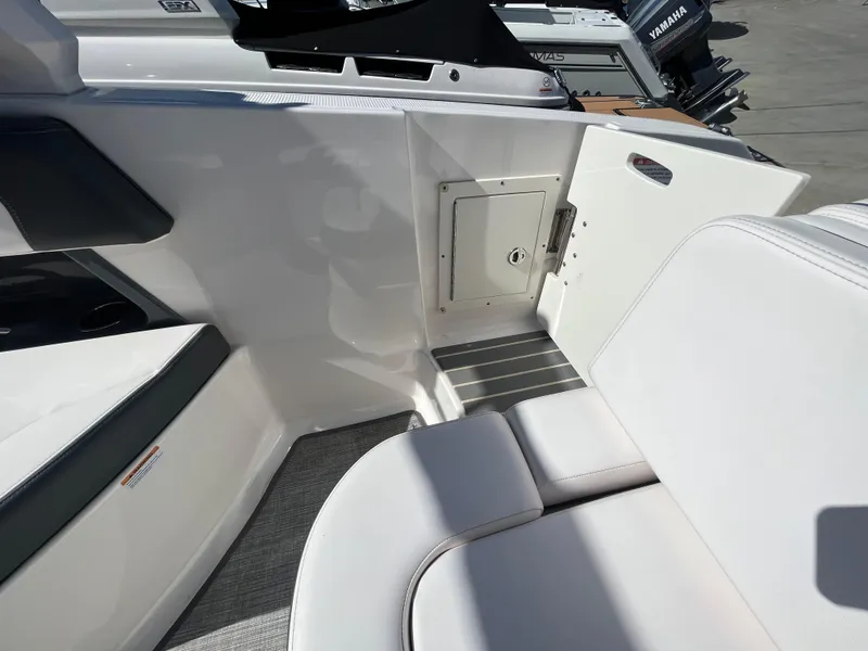 Slide: The Image of 2019 Chaparral 277 SSX boat interior with white seating and storage compartment. - 43