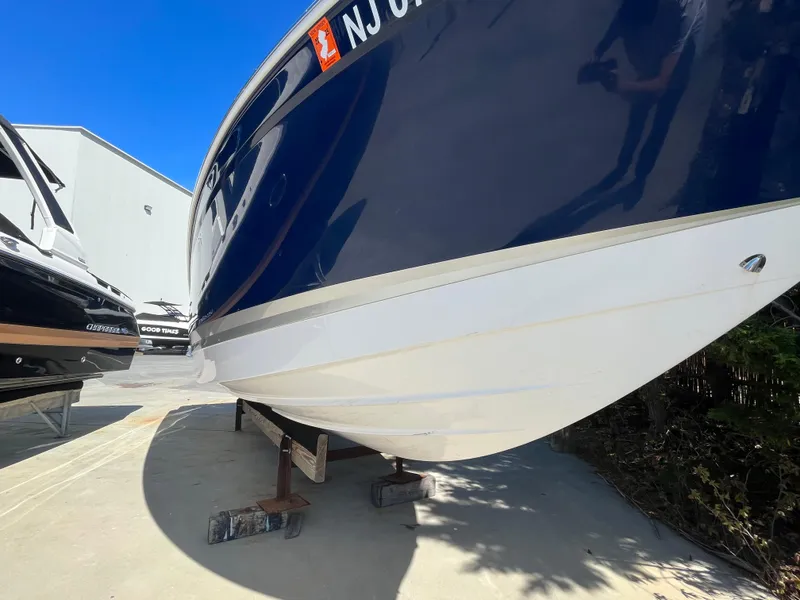 Slide: The Image of 2019 Chaparral 277 SSX boat on dry dock, blue and white hull, sunny day. - 5