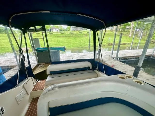 Slide: The Image of 1998 Rinker Fiesta Vee 266 boat interior with seating and canopy, docked by a grassy area. - 11